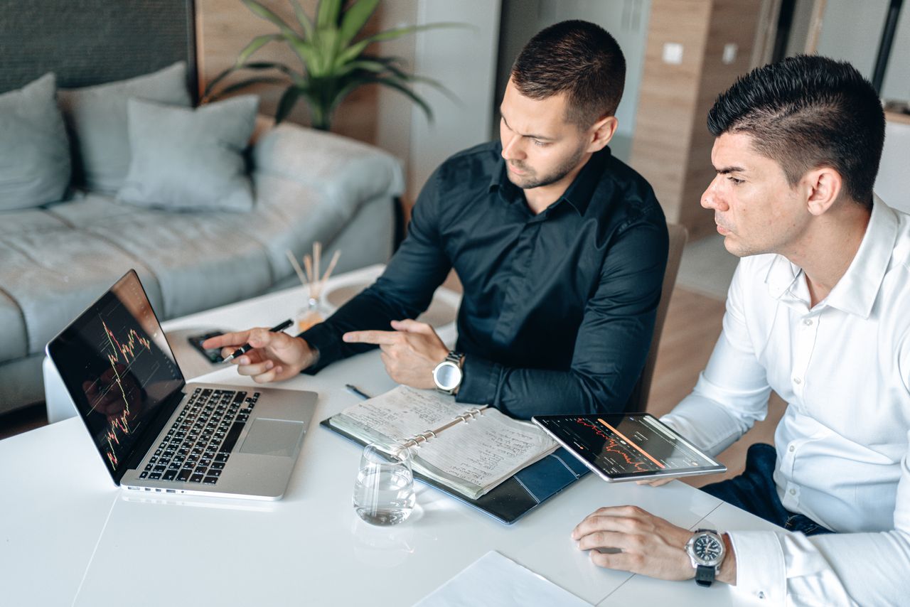 Crafting Captivating Headlines: Your awesome post title goes here Two men in a business meeting analyzing digital charts on laptop and tablet.