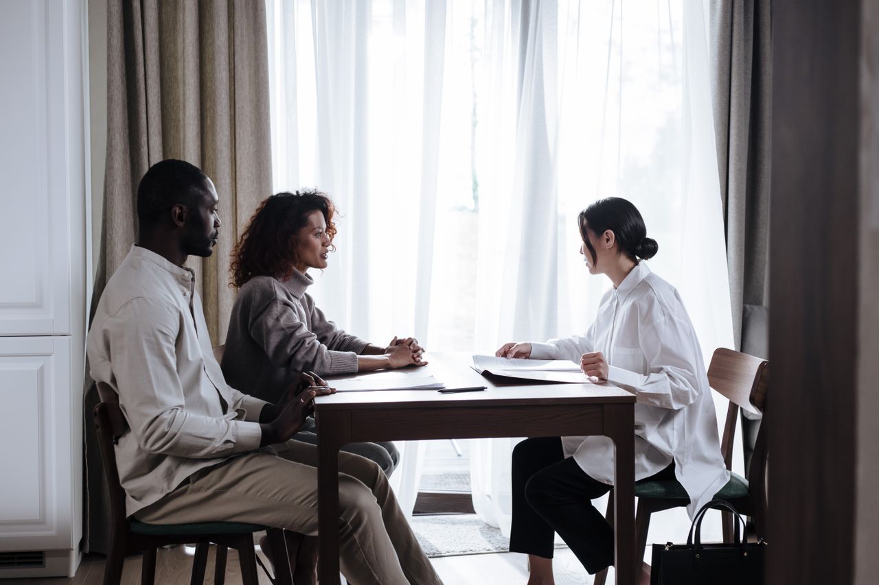 services-03 Three adults engaged in a discussion with documents at a table indoors, emphasizing collaboration.